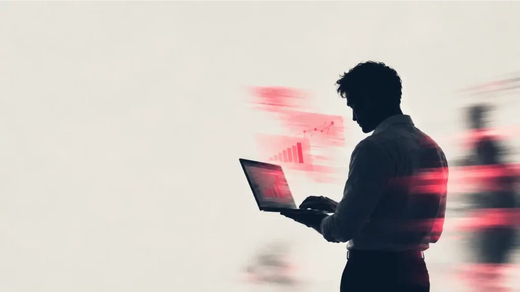 Uomo in controluce che consulta un portatile con grafici di crescita in rosso, per rappresentare il budget delle campagne Meta Ads
